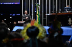 Senador Eduardo Braga discursa na tribuna do plenario do Senado com cocares indigenas em primeiro plano