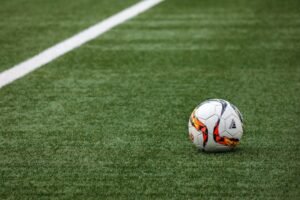 Bola de futebol oficial parada em campo de grama com linha branca lateral