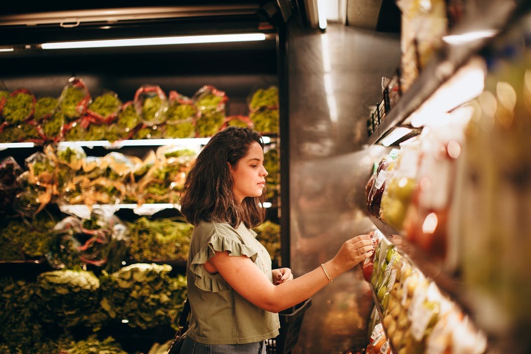 Mulher escolhendo verduras frescas em corredor de supermercado