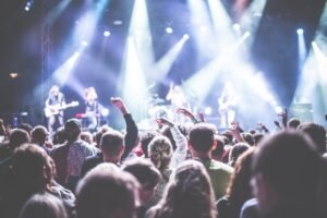 Plateia de show com bracos levantados em frente a palco iluminado com banda
