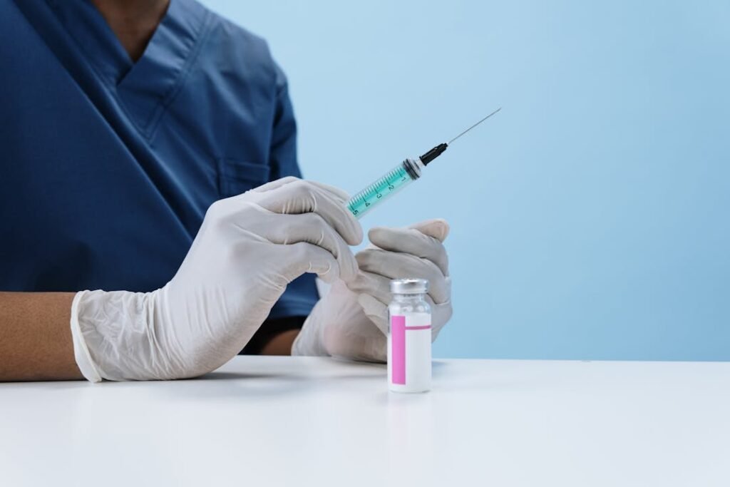 Profissional de saude com luvas brancas preparando seringa de vacina em frasco