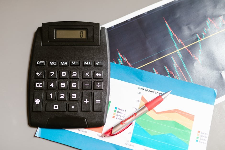 Calculadora preta sobre relatórios financeiros com caneta