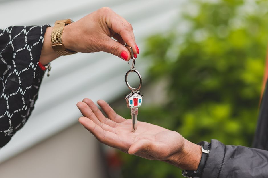 Mão entregando chave de casa em formato de casinha