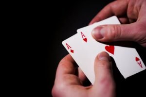 Mãos segurando cartas de baralho contra fundo escuro