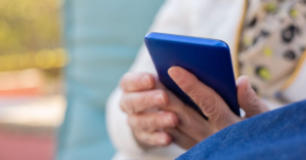 Mãos de pessoa idosa usando smartphone para acessar o Meu INSS