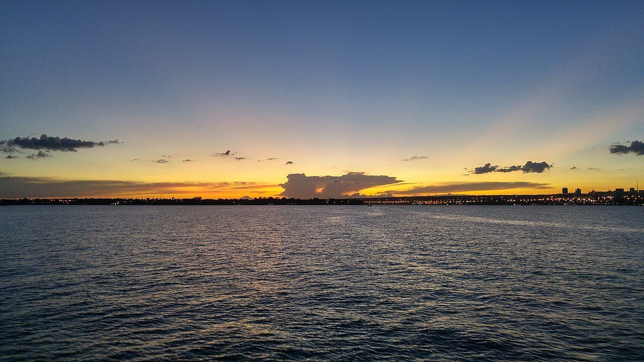Vista do Lago Paranoá, em Brasília, ao entardecer, com a orla da cidade ao fundo
