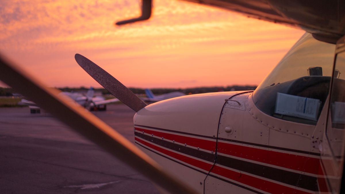 Avião de pequeno porte no pátio de um aeródromo ao pôr do sol