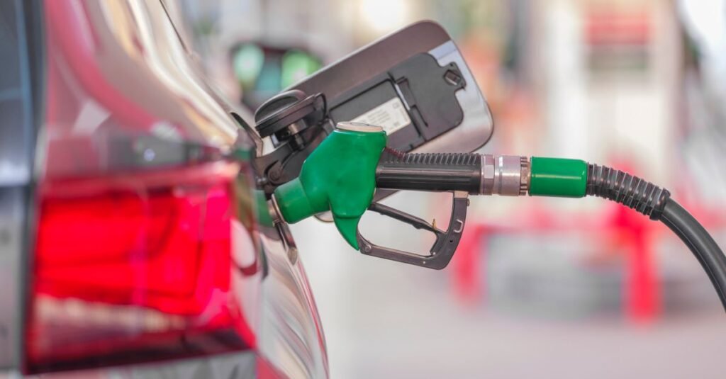 Bico verde de abastecimento inserido no tanque de um carro em posto de combustivel