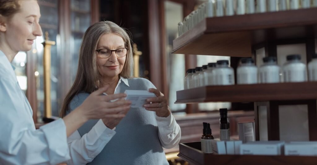 Cliente confere a caixa de um medicamento ao lado de farmacêutica em farmácia