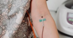 Braço de paciente com dispositivo de acesso venoso fixado por curativo em ambiente hospitalar