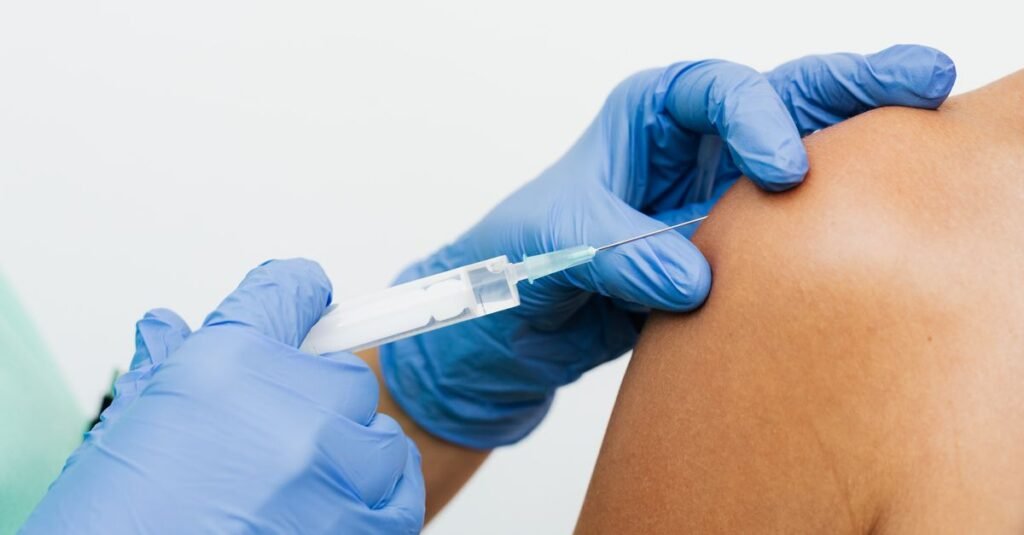 Profissional de saúde com luvas aplica vacina no braço de uma pessoa