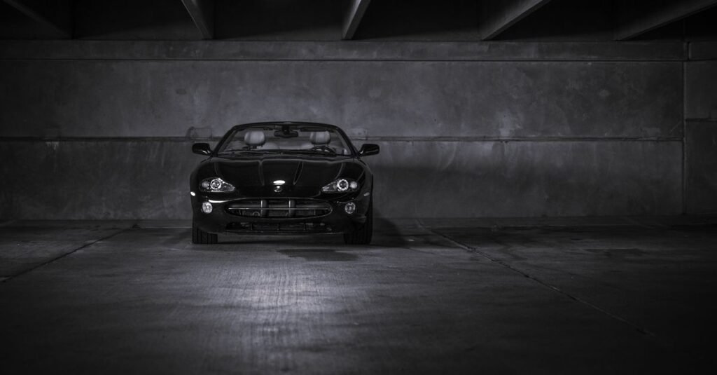 Carro esportivo preto estacionado em garagem escura de prédio