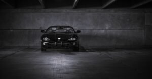 Carro esportivo preto estacionado em garagem escura de prédio