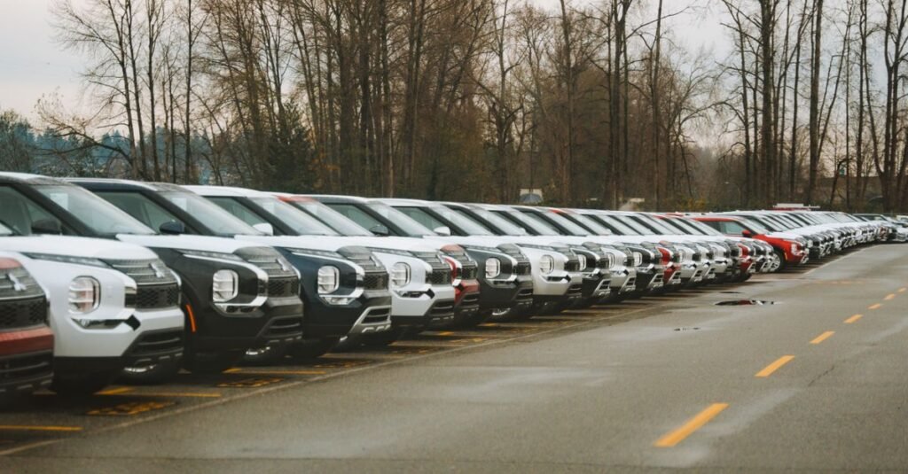 Fileira de carros novos estacionados em pátio de concessionária