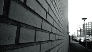Muro de tijolos em preto e branco visto em perspectiva, com rua ao fundo