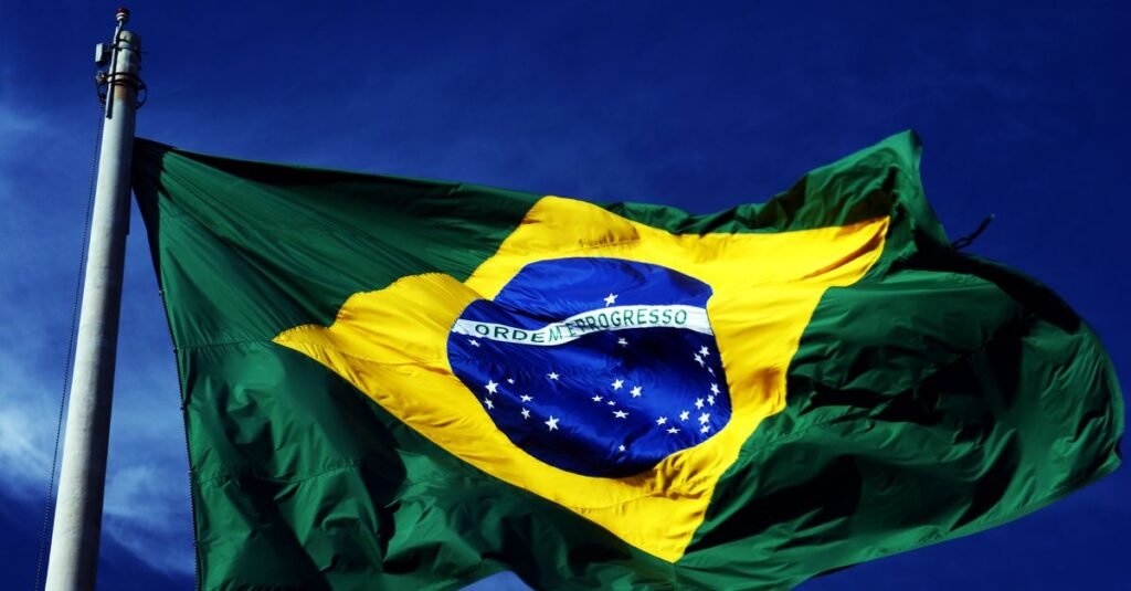 Bandeira do Brasil tremulando em mastro sob ceu azul