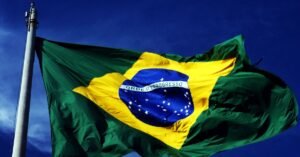 Bandeira do Brasil tremulando em mastro sob ceu azul
