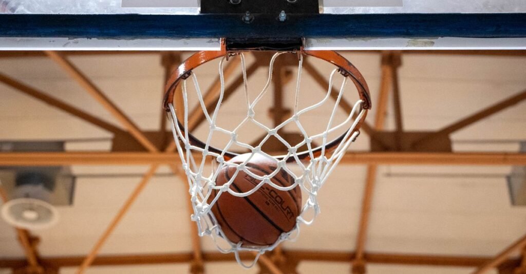 Bola de basquete entra na cesta em ginasio coberto
