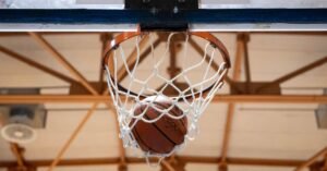 Bola de basquete entra na cesta em ginasio coberto