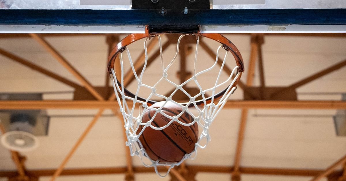 Bola de basquete entra na cesta em ginasio coberto