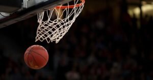Bola de basquete entra na cesta durante jogo em ginásio