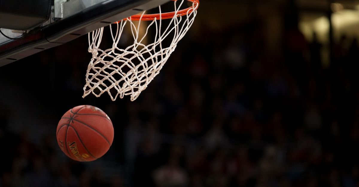 Bola de basquete entra na cesta durante jogo em ginásio
