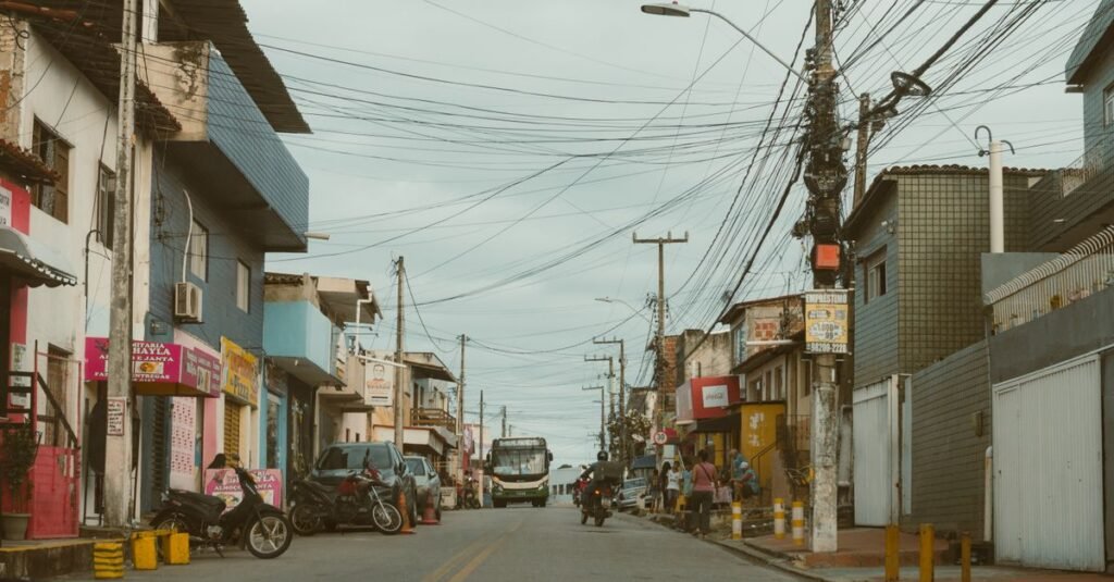 Rua comercial brasileira com lojas, motos e ônibus em dia nublado