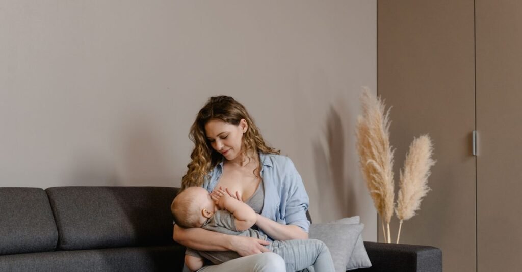 Mãe sentada em sofá amamentando o bebê no colo