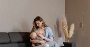 Mãe sentada em sofá amamentando o bebê no colo