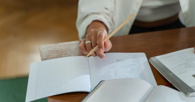 Candidata faz anotações a lápis em caderno durante estudo para concurso público