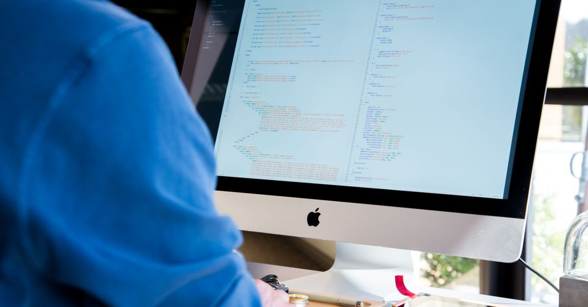 Pessoa programando em computador com linhas de código na tela