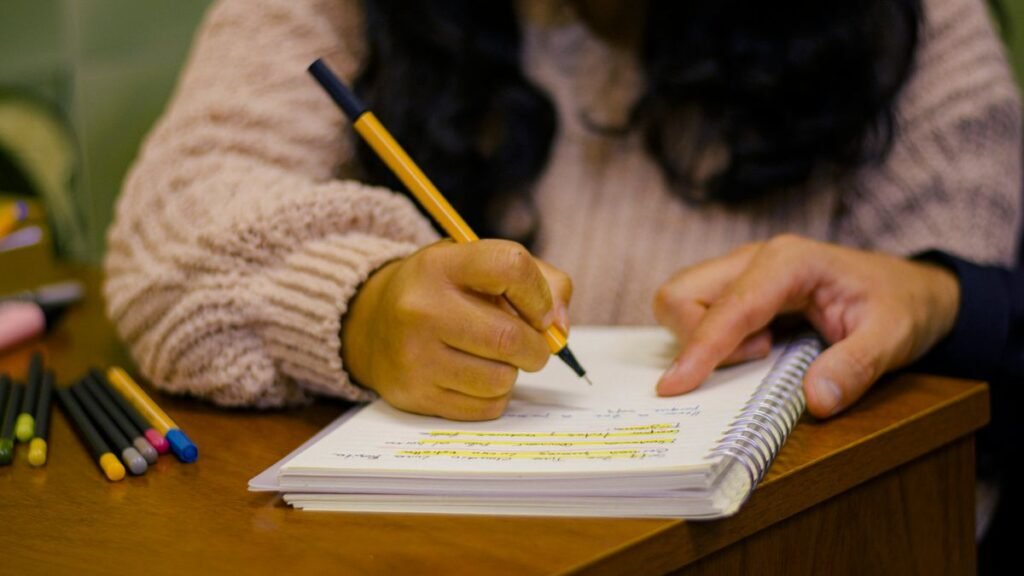 Pessoa faz anotações em caderno durante estudo para concurso