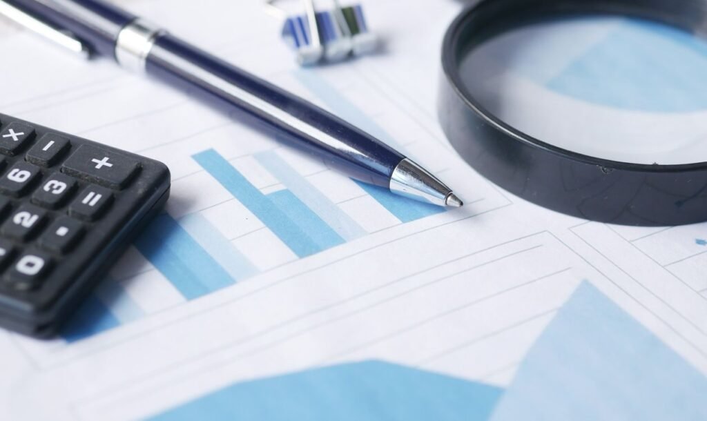 Calculadora, caneta e lupa sobre relatórios financeiros