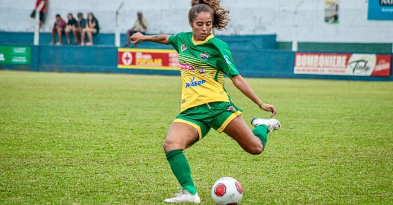 Jogadora chuta a bola durante partida de futebol feminino