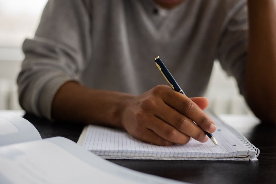 Estudante adulto escreve em caderno durante aula