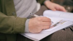 Estudante escreve em caderno durante preparação para prova