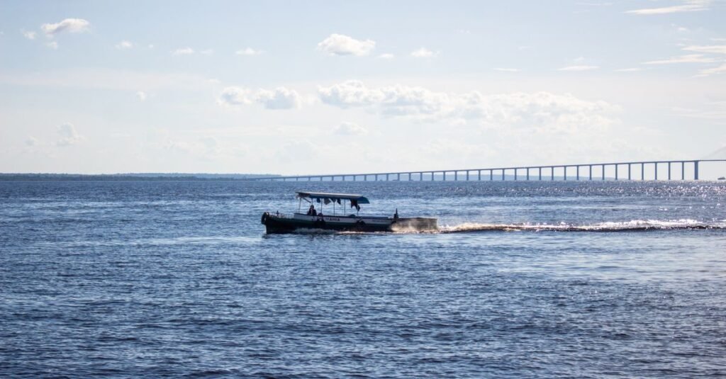 Barco regional de passageiros navega no Rio Negro com a ponte de Manaus ao fundo