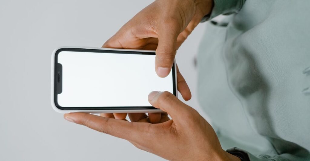 Mãos segurando um celular com a tela em branco