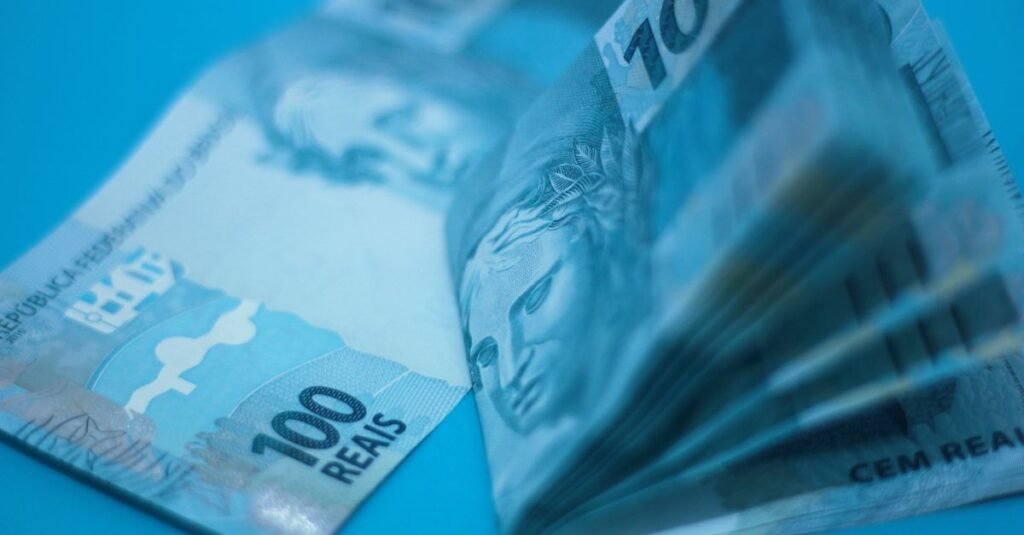 Cédulas de cem reais sobre fundo azul em close
