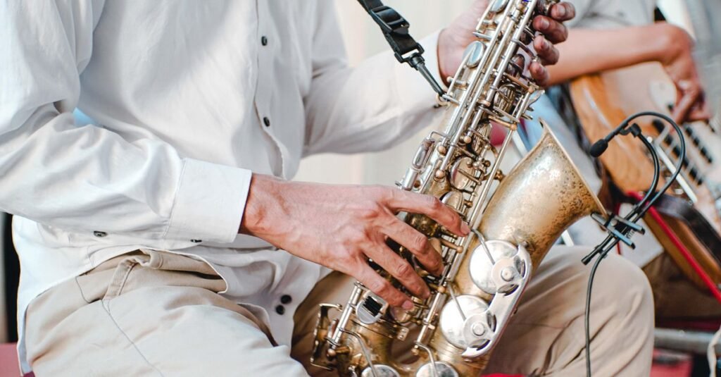 Músico tocando saxofone em apresentação ao vivo, em primeiro plano as mãos sobre as chaves do instrumento
