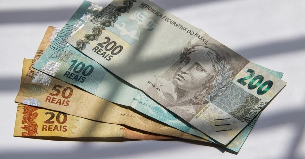 Cédulas de real de 200, 100, 50 e 20 dispostas sobre superfície clara