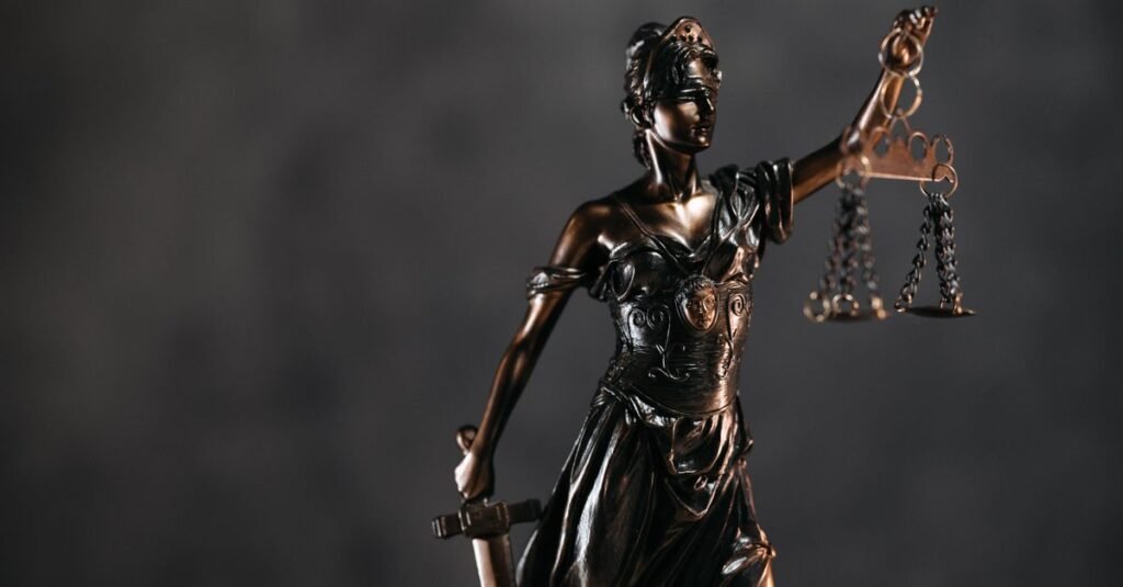 Estatua da Justica em bronze segurando a balanca, fundo escuro
