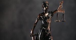 Estatua da Justica em bronze segurando a balanca, fundo escuro