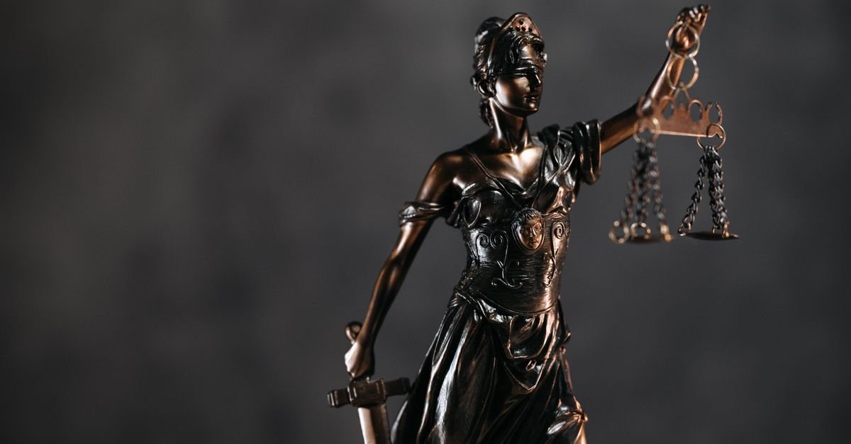 Estatua da Justica em bronze segurando a balanca, fundo escuro