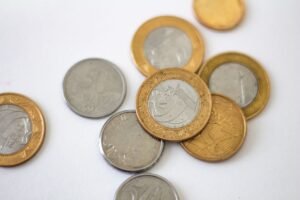 Moedas de real brasileiro espalhadas sobre superfície clara