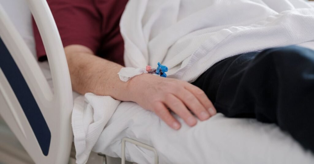 Braco de paciente internado com acesso venoso em leito hospitalar