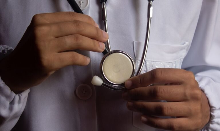 Médico de jaleco branco segura estetoscópio em closeup