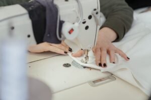 Mãos de costureira trabalham em máquina de costura