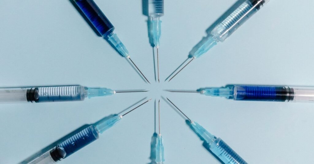 Seringas de vacina dispostas em círculo sobre fundo azul