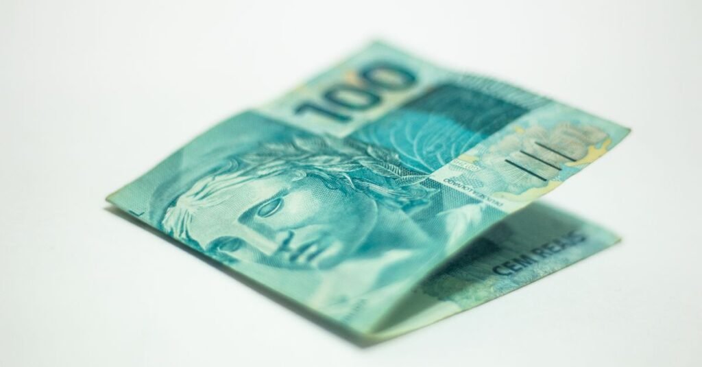 Nota de cem reais dobrada sobre fundo branco em close